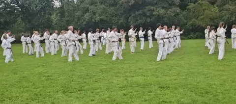 Lange rijen karateka's oefenen technieken voor de bosrand