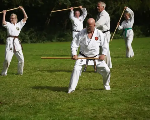 Gemengde groep oefent staftechnieken op het veld