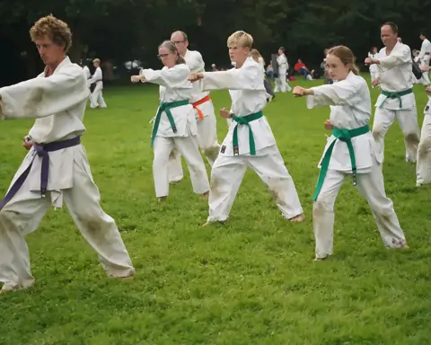 Karateka's oefenen stoottechnieken met publiek op de achtergrond