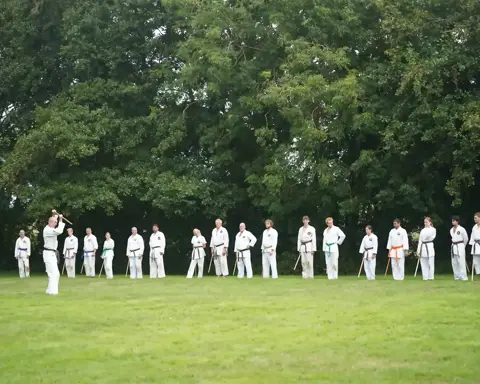 Sensei demonstreert een jo-techniek aan de opgestelde groep