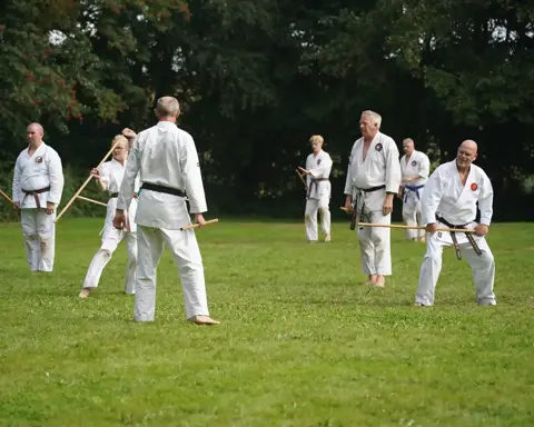 Jonge karateka met jo-staf tijdens de buitentraining