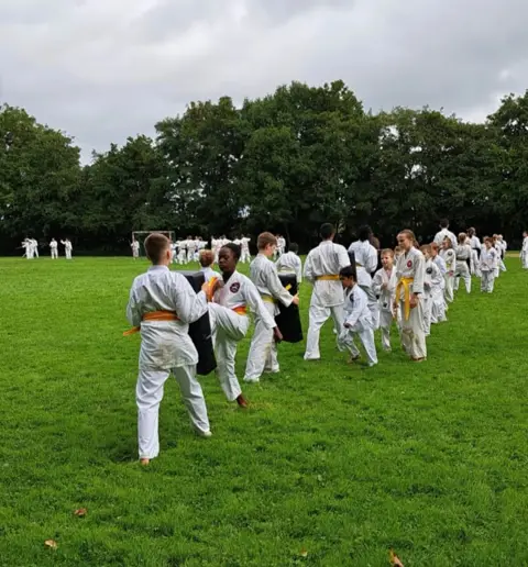 Rijen karateka's oefenen kata op het veld in Wieringerwerf