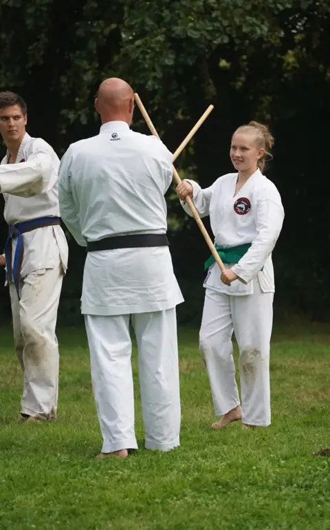 Sensei geeft een jonge karateka uitleg over het werken met de jo