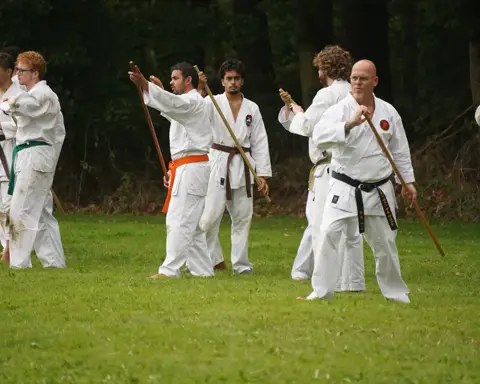Karateka's houden de jo-staf omhoog tijdens de oefening