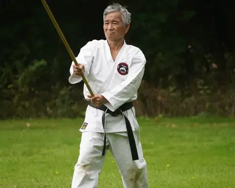 Ervaren karateka met zwarte band en jo-staf tijdens de gasshuku