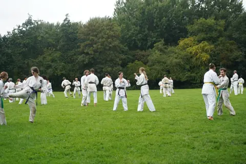 Karateka's oefenen in tweetallen aan de rand van het veld