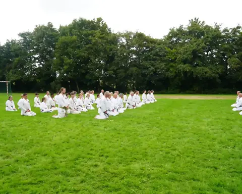 Deelnemers zitten in seiza op het grasveld