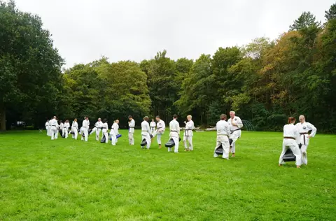 Karateka's knielen op het veld tijdens een oefening