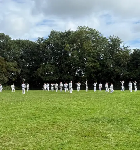 De groep traint in de verte op het veld onder een wolkenlucht