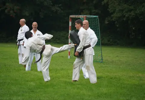 Karateka trapt op een stootkussen dat een partner vasthoudt