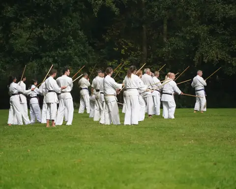 Grote groep karateka's traint gezamenlijk met de jo-staf