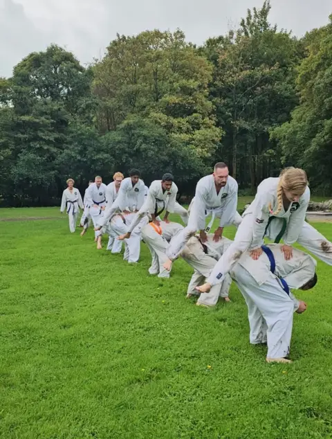 Karateka oefent een techniek met de groep op de achtergrond