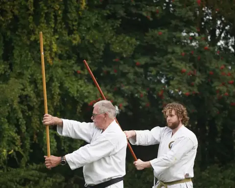 Twee karateka's oefenen samen met de jo-staf