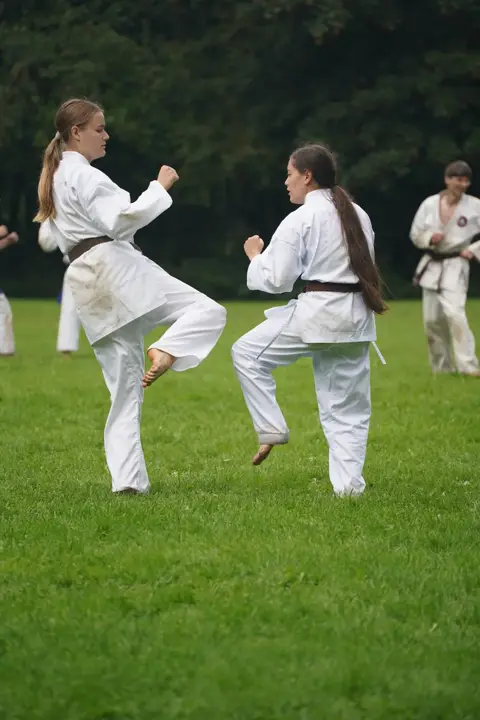 Twee jonge karateka's oefenen een voorwaartse trap