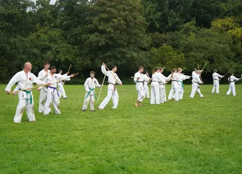 Groep oefent stoottechnieken in rijen op het veld