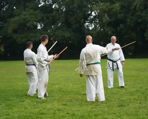 Partneroefening met de jo-staf onder begeleiding van de sensei