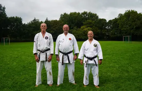 Drie zwarte banden poseren op het grasveld
