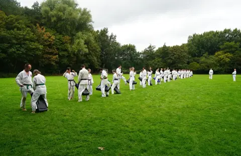 Karateka's buigen in rijen naar de sensei