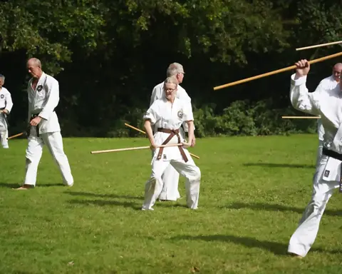 Karateka's oefenen partnerwerk met de jo-staf