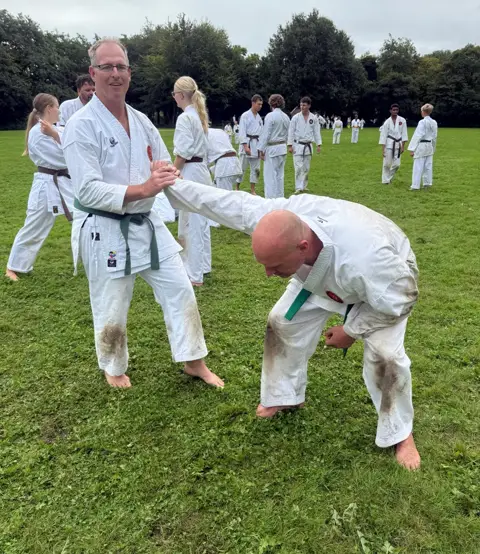 Sensei corrigeert de houding van een deelnemer