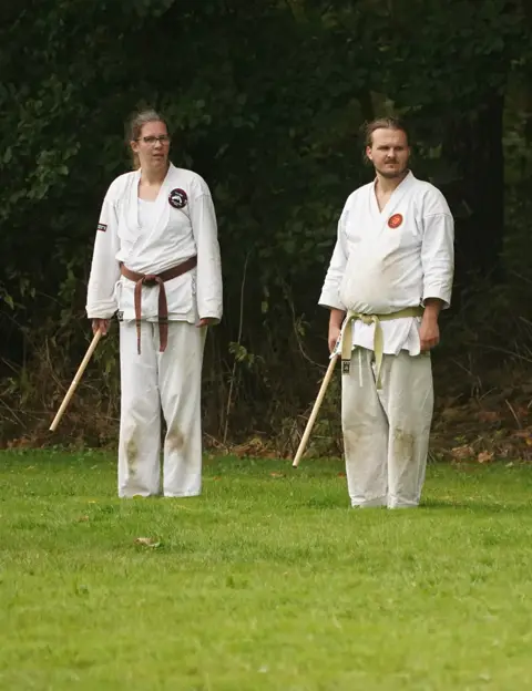 Twee karateka's poseren met hun jo