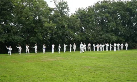 Lange rij karateka's aan de rand van het trainingsveld
