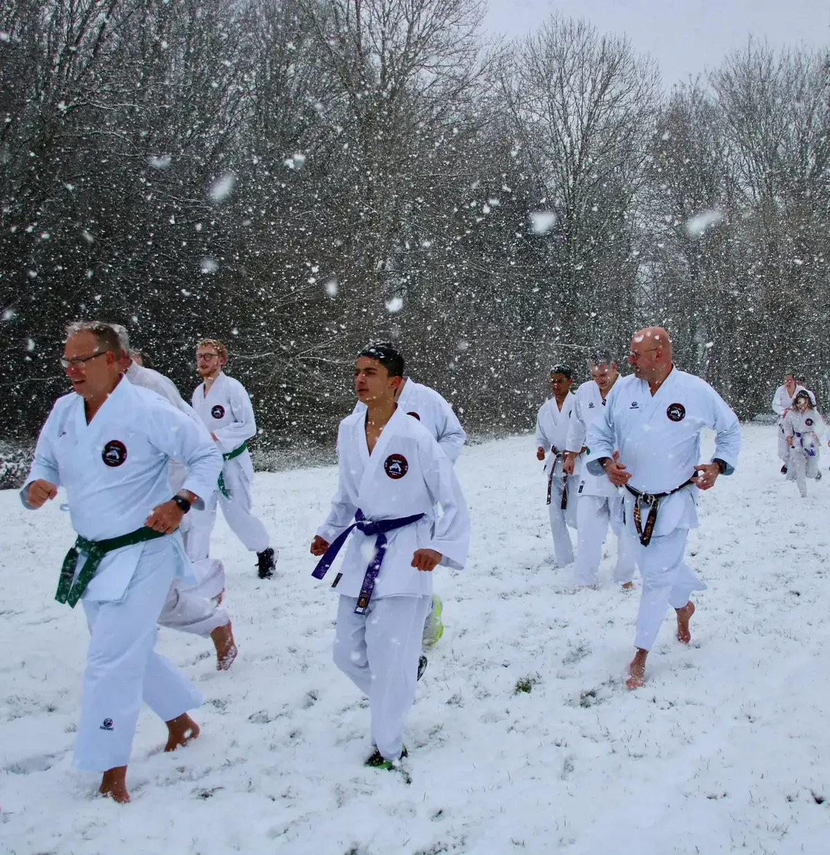 Volwassenen en jeugd rennen samen door de sneeuw tijdens wintertraining