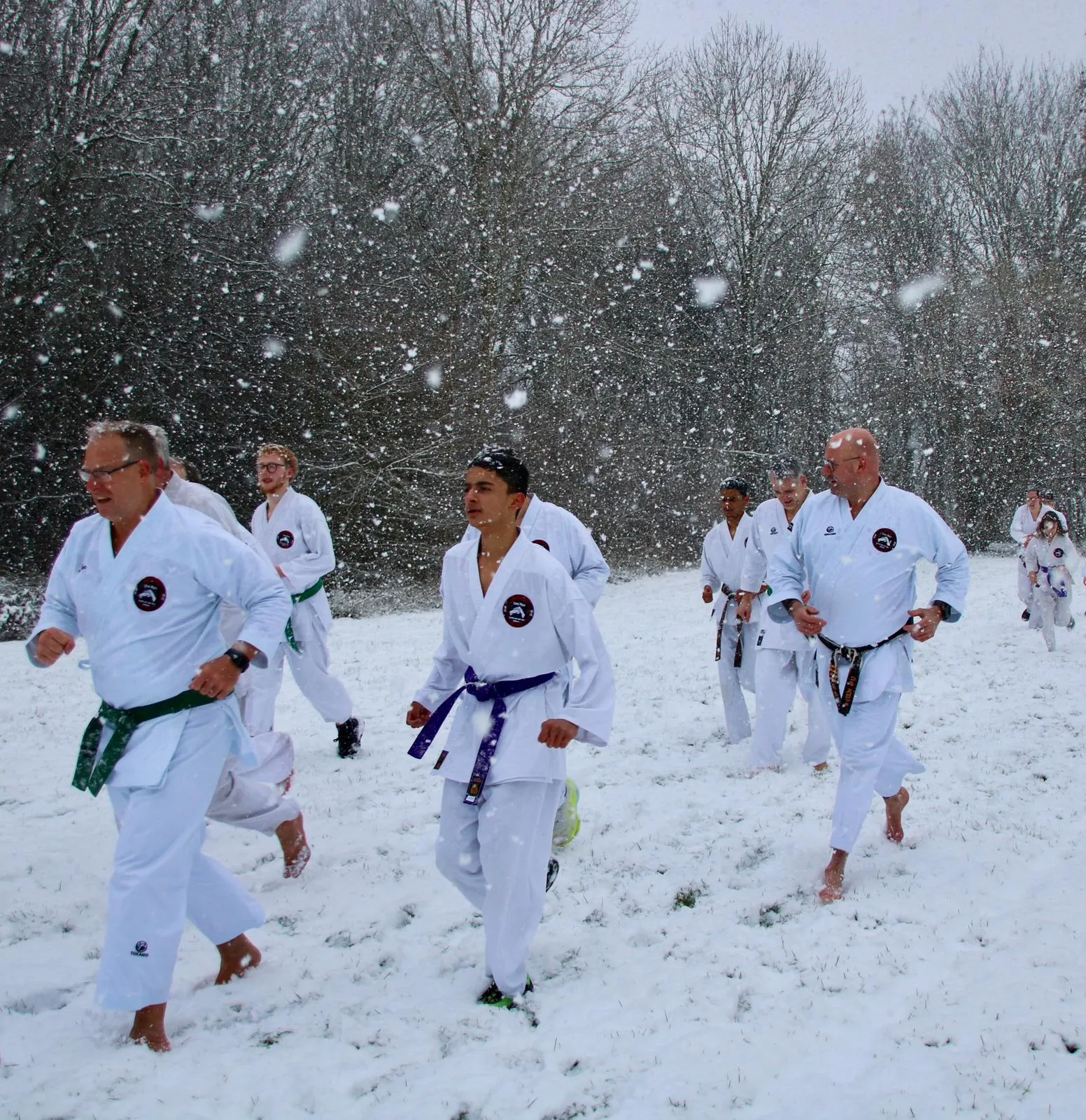 Volwassenen en jeugd rennen samen door de sneeuw tijdens wintertraining