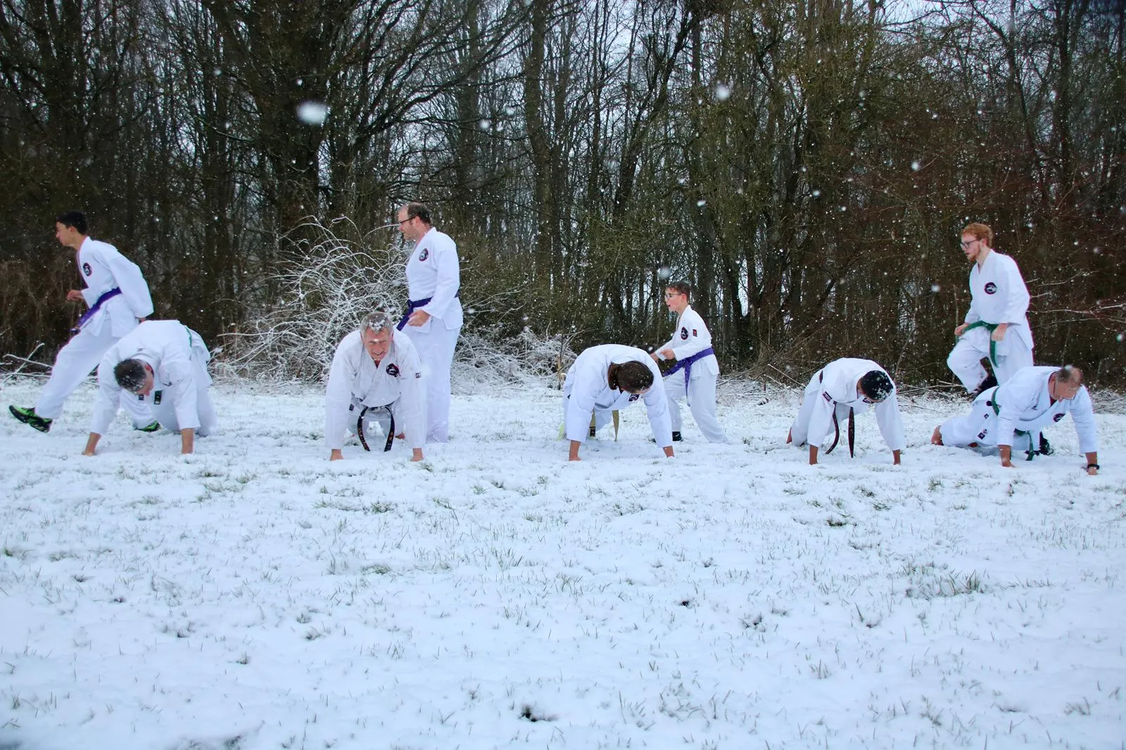 Karateleerlingen doen push-ups en oefeningen in de sneeuw