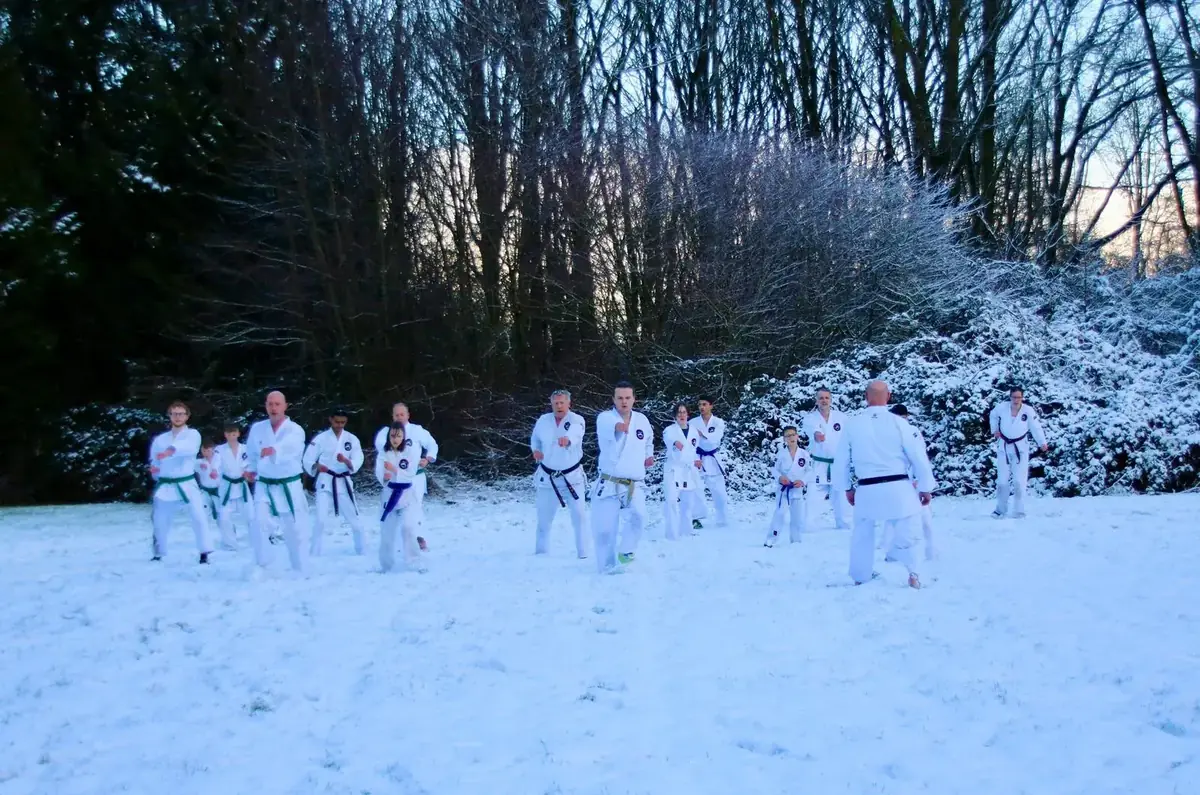 Karategroep traint basistechnieken in besneeuwd bos