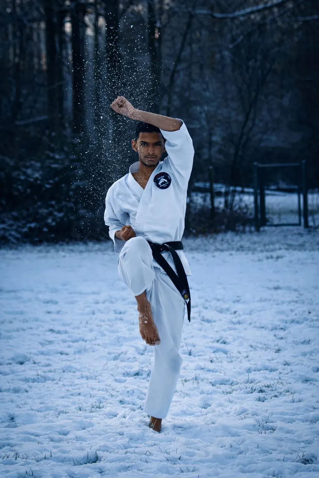 Karateka voert hoge trap uit in de sneeuw